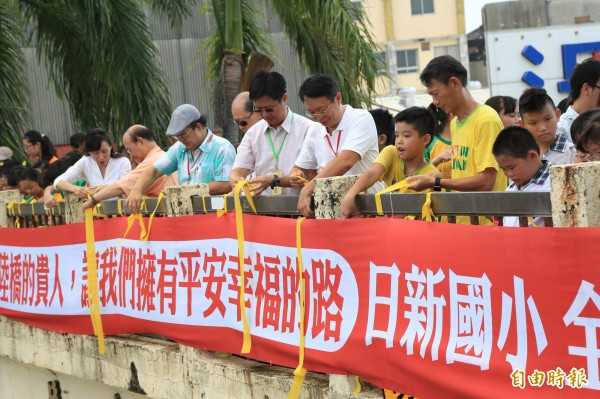 南市南區日新國小親師生們走上明賢人行陸橋繫上黃絲帶、表達追思感恩。（記者王俊忠攝）