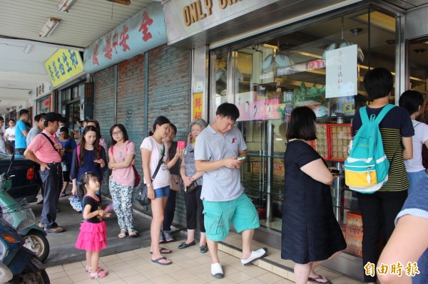 從店家騎樓前排隊的人龍，看出店家生意興隆，民眾排隊2個多小時，就是要吃這家店的蛋黃酥月餅。（記者張聰秋攝）