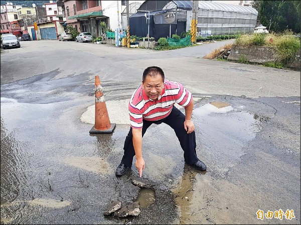 關西鎮代會主席劉德樑手指處路面柏油，被滲漏水沖破。（記者黃美珠攝）