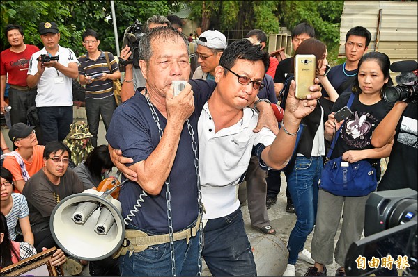 高雄市政府昨動員警力配合農業局拆遷牴觸果菜市場住戶，居民身綁鐵鍊、持桶裝瓦斯抗爭，宣示「死守家園、打死不退」，拆除現場氣氛緊繃。（記者張忠義攝）