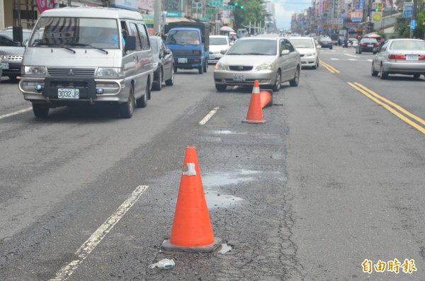 近日豪雨造成屏東市路面坑坑洞洞，工務單位放置三角錐提醒駕駛人。（記者葉永騫攝）