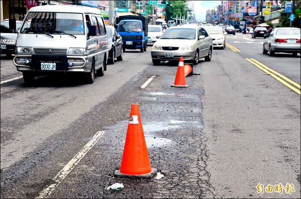 屏東大雨造成路面坑坑洞洞，工務單位放置三角錐提醒駕駛人。（記者葉永騫攝）