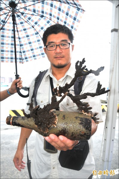 基隆市產發處、海科館及區漁會昨天於碧砂漁港舉辦「淨港」活動，潛水人員下到漁港海底，赫然發現鹿角珊瑚竟長在鏮棄玻璃瓶上。（記者俞肇福攝）