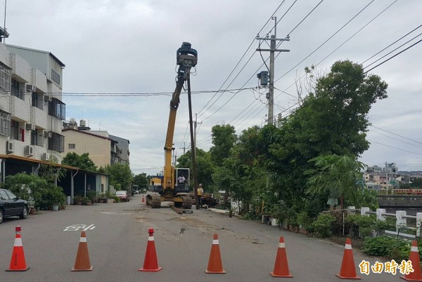 梧棲大排護岸傾斜，造成路面塌陷，目前先以鋼軌樁固定。（記者黃鐘山攝）