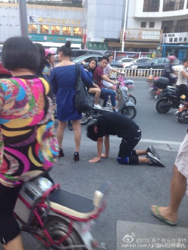 一名女子用狗鍊項圈栓著一名男子在路上逛街，適逢下班時間，許多民眾紛紛被這一幕嚇傻。（微博）