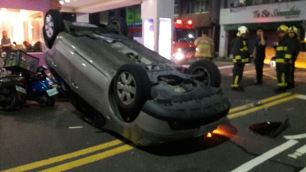 颱風夜不平靜鬧區2車擦撞，轎車四輪朝天翻覆路口，令人怵目驚心，所幸駕駛僅受輕傷送醫。（記者黃良傑翻攝）