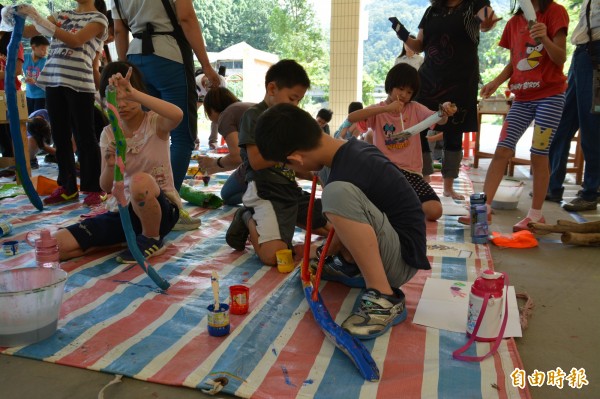 新竹縣大坪國小學童今天參加南外社區的蝴蝶生態彩繪活動，把撿來的漂流木畫成漂亮的「毛毛蟲」。（記者蔡孟尚攝）