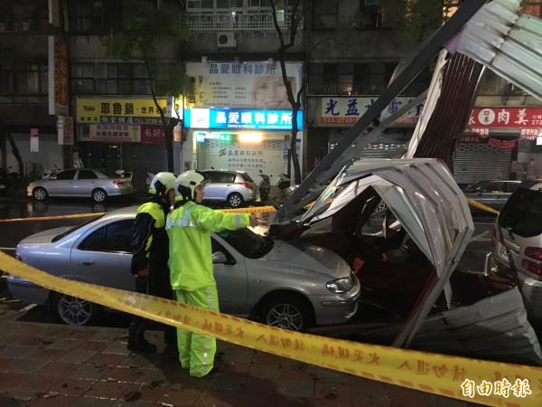 台北市莊敬路一棟公寓頂加的鐵皮屋頂被強風吹落，砸毀路邊停放轎車，警消到場警戒。（記者姚岳宏攝）