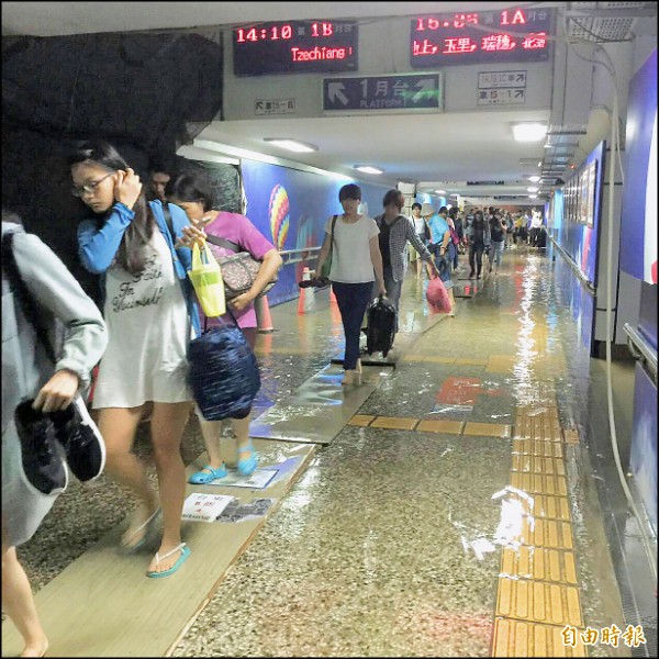 台東暴雨，台東火車站地下道也淹水，旅客小心翼翼走木棧板。（記者王秀亭攝）