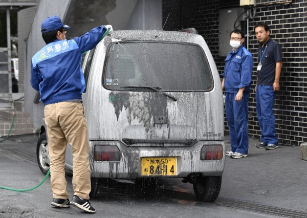 火山噴發之後，車上都被覆蓋的厚厚一層火山灰，圖為政府人員在清潔車輛。（路透）