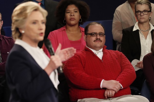 一身搶眼紅衣的肯˙波恩9日在第2場美國總統候選人電視辯論會現場聆聽民主黨總統候選人希拉蕊發言。（美聯社）
