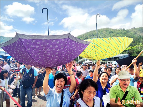 大批遊客聚集在碼頭，拿起網子或倒放雨傘搶接從漁船上拋下的包子，開心「滿載而歸」。（記者江志雄攝）