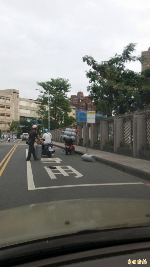 載運瓦斯桶的機車因綑綁不牢，2桶瓦斯桶當街掉落，險些砸中後車，險像環生。（記者吳仁捷攝）