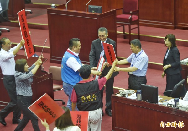 台北市長柯文哲下午前往市議會做報告，國民黨議員舉海報表達訴求。（記者方賓照攝）