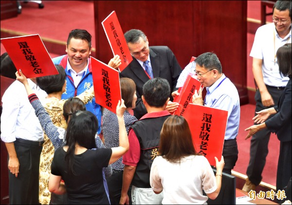 市長柯文哲昨日前往市議會做報告，國民黨議員舉海報表達訴求。（記者方賓照攝）