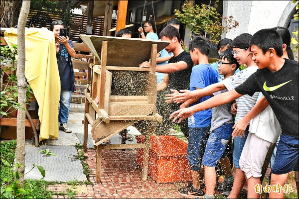 新竹高鐵站旁小農市集平台「承山種籽樹」小舖昨天開幕，邀請小朋友操作土礱和風鼓，讓稻米脫殼，再自己洗米煮成飯。（記者廖雪茹攝）