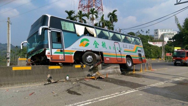 全航客運撞上草屯鎮中潭公路炎峰橋頭中央分隔島，逾半車身卡住，動彈不得。（圖：南投縣府消防局提供）