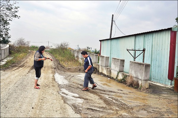 林姓住戶（右）昨跟市議員王美惠（左）陳情，住家後方唯一便道雨後泥濘積水，出入鞋子、褲管都要注意腳步，以免弄髒。（記者王善嬿攝）