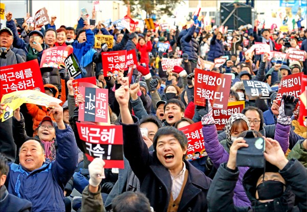 南韓國會九日表決彈劾總統案，場外集結的民眾舉著「把朴槿惠關起來」、「沒彈劾、沒國會」等標語，在聽到彈劾案過關後振臂歡呼。（美聯社）