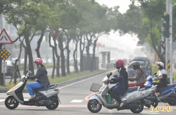 前金區天空呈現霧濛濛一片，機車騎士戴上口罩防護。（記者黃志源攝）