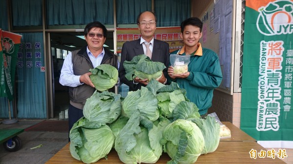 將軍區農會總幹事吳明成（中）、推廣部主任林彥良（左）叫賣義賣的高麗菜，1顆30元，泡菜1包60元。（記者楊金城攝）