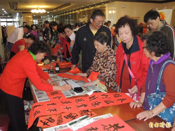 新竹市長和宮今舉行補運法會，由於農曆年將近，加上景氣不好，風城老字號公益社團新竹市媽祖功德會也在會場同步舉行春聯揮毫贈送活動，先後湧入逾萬祈福補運、排隊索取春聯的人潮。（記者王駿杰攝）