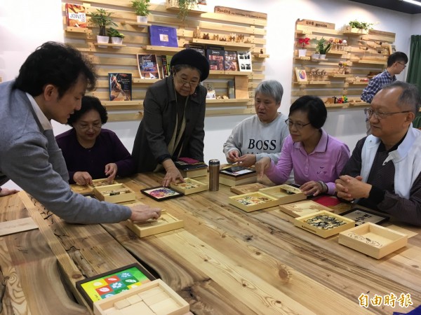 信誼基金會推出長者手作「人生記憶寶盒」的木作課程，一群長者專注地聆聽老師的說明。（記者林曉雲攝）