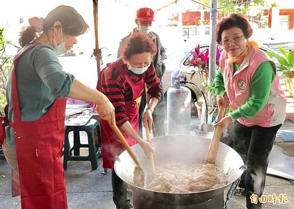 邱素貞（右）與志工依循古法炊製年糕，邊放糯米漿塊邊用鍋鏟、木棒攪拌。（記者黃鐘山攝）