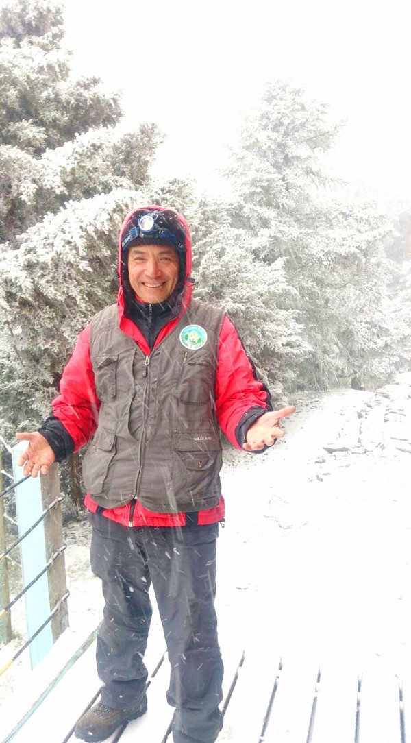 A worker at Yushan National Park Headquarters in Nantou County smiles as he stands in the falling snow yesterday morning.
Photo: courtesy of Yushan National Park Headquarters