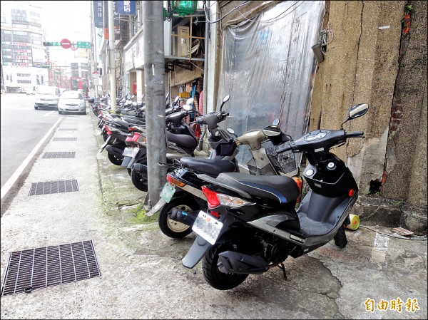 基隆道路評比墊底，像圖中的人行道被騎士停放機車，造成行人要走在馬路上與車爭道。（記者俞肇福攝）