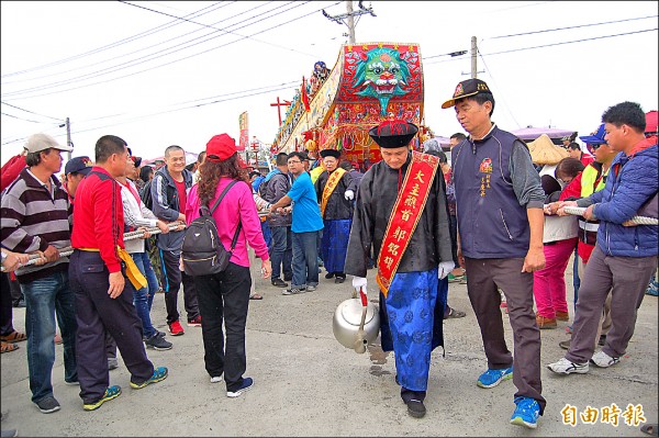 大主醮首郭銘雄持大茶壺，沿路灑水、開路，為王船開水路。（記者楊金城攝）