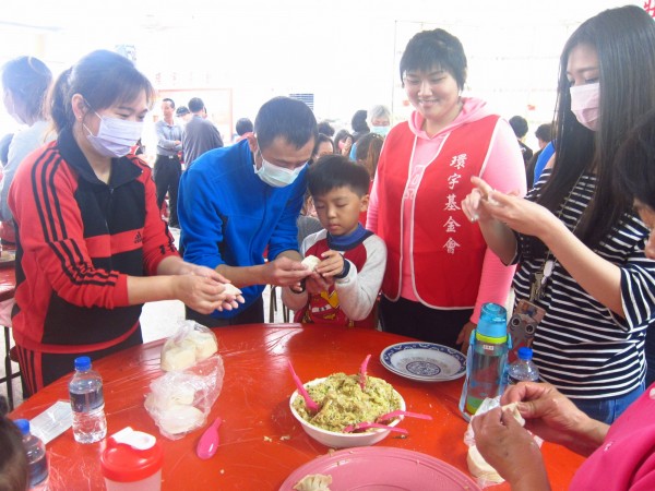 大人小孩努力包水餃。（記者羅欣貞翻攝）