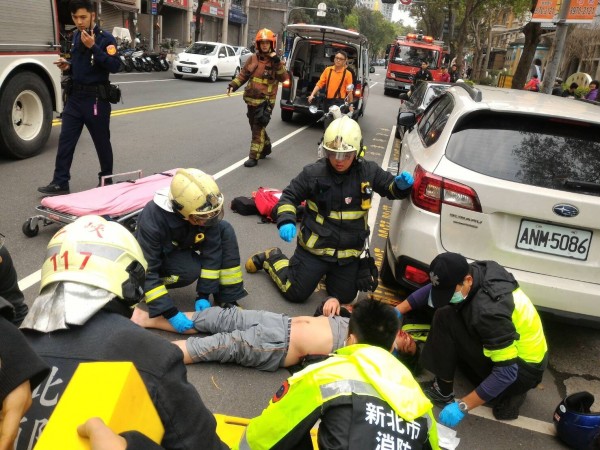 一名騎士騎車時摔車撞上路邊轎車，消防人員到場救治。（記者吳仁捷翻攝）