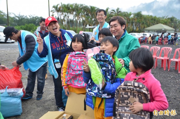 陳圓圓（戴紅帽者）開心發放球鞋和書包給小朋友。（記者陳鳳麗攝）