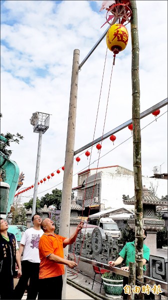 吊車吊起數支長竹，安插在預先挖好的基座，再升上燈籠，宣示建醮活動開始，燈篙於16尺處掛上天燈。（記者黃明堂攝）