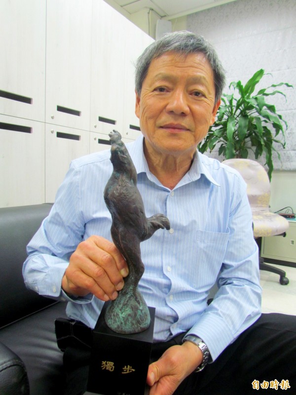 王英信和他設計的「獨步」獎座，主角是裸體台灣鬥雞。（記者陳鳳麗攝）