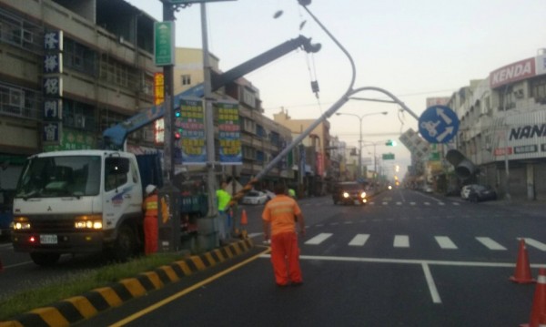 交通號誌桿連同電線整支被扯斷倒在道路上，警方及台電連忙吊起移除。（記者湯世名翻攝）