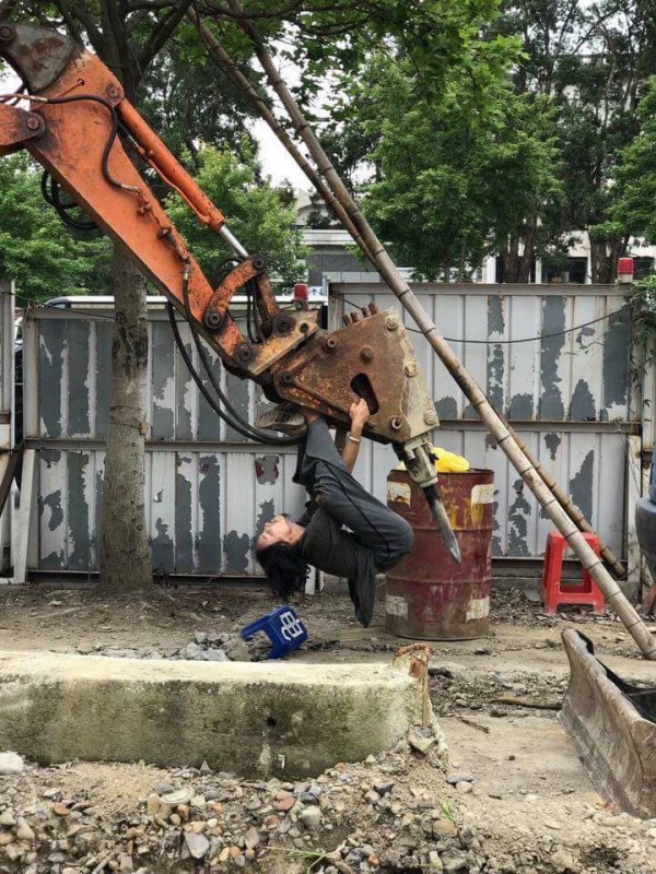 一名網友在「爆料公社」臉書上傳一張照片，只見正在作業中的怪手，一名民眾竟將手腳勾住怪手，整個人吊掛在機器。（圖擷取自爆料公社）