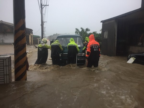 氣象局表示，今明兩天是雨勢最強的時候，各地都須特別留意下雨情形。圖為北海岸大雨，馬路變水道，消防人員協助拋錨汽車脫困。（新北消防局提供）