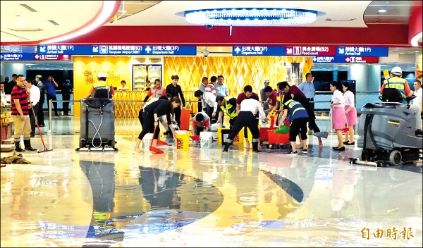 2日上午一場暴雨導致桃園機場第二航廈禮品大街淹水，工作人員趕忙清理積水。（記者朱沛雄攝）