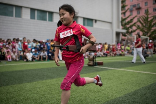 北韓女童拿仿真的AK47步槍，奮力向前奔跑。（法新社）