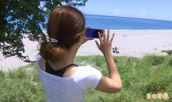 跟羅男一起環島的女友在岸邊用手機記錄整個過程。(記者王秀亭攝) 跟羅男一起環島的女友在岸邊用手機記錄整個過程。(記者王秀亭攝)