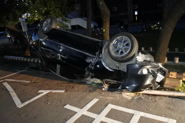 肇事自小客車橫越對向車道，衝撞人行道護欄護欄翻覆，駕駛及2名乘客逃逸無蹤。（記者陳賢義翻攝）