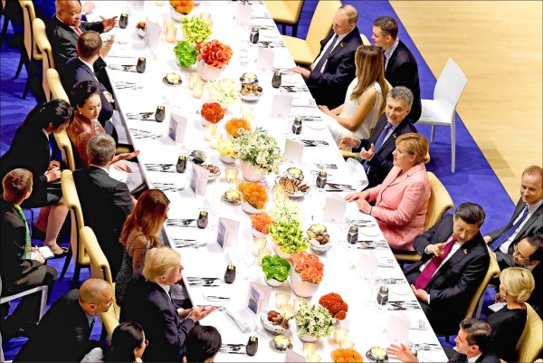 二十國集團領袖高峰會七日晚間在德國漢堡舉行晚宴，來自十九國與歐盟的領袖和其伴侶沿著長桌兩側入座，場面壯觀。晚宴出席者（右排由上而下）依序為俄羅斯總統普廷、美國第一夫人梅蘭妮亞、阿根廷總統馬克里、德國總理梅克爾以及中國國家主席習近平。（法新社）