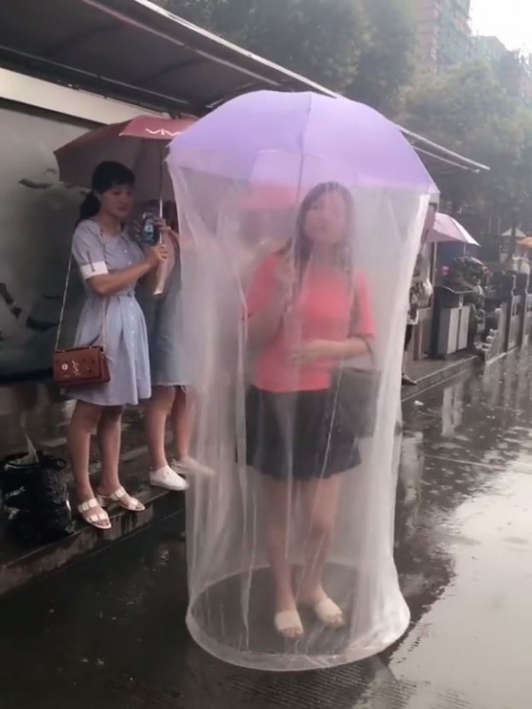 有女子突發奇想，在雨傘上加了一層塑膠套，但女子撐傘的畫面在網路流傳後，卻遭網友笑說看起來就像大型的保險套。（圖擷自「瓜瓜娛樂」臉書）