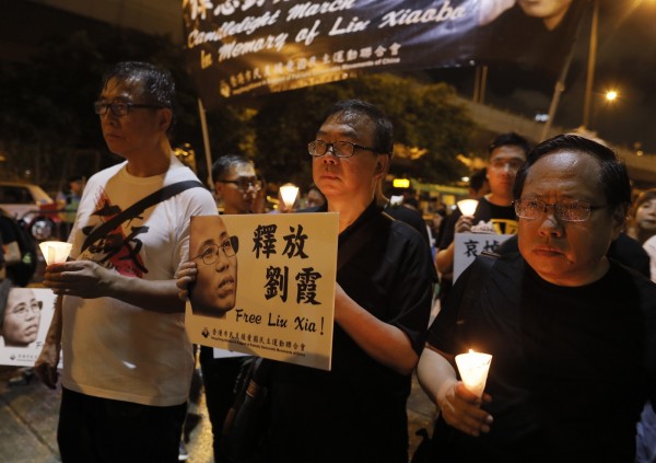 為哀悼中國民主鬥士劉曉波過世，香港支聯會於週六晚間舉行燭光遊行，，參與民眾不畏雨勢，以鮮花與燭光向劉曉波致意。（美聯社）