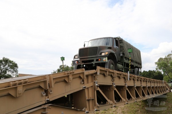 陸軍中型戰術輪車在戰備演練時，通過MGB中框橋。圖中的戰術輪車因有擔任行政車輛需求，有加裝防捲入裝置。（圖：軍聞社）。