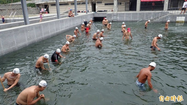 台東縣水中運動協會救生員班結訓學員拿掃把在水中掃青苔。（記者黃明堂攝）