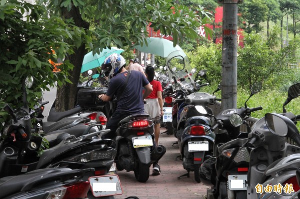 機車違規停放在人行道兩旁，民眾通過時不小心還會被排氣管燙傷。（記者吳昇儒攝）