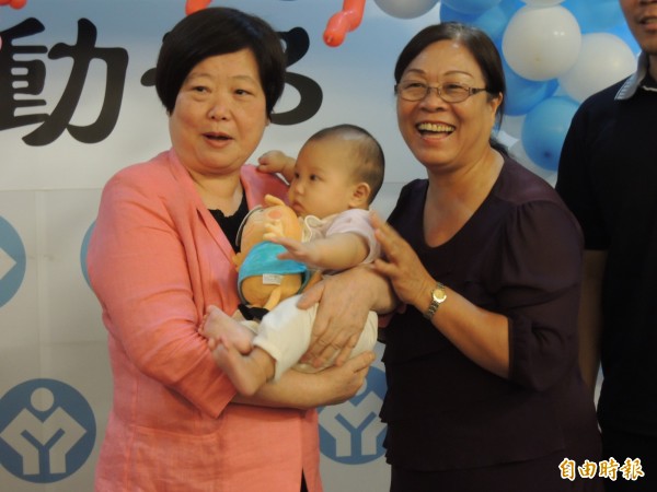 勞動部舉辦親子日活動，已經當阿嬤的部長林美珠（左），看到小小孩每個都要抱一抱。（記者黃邦平攝）
